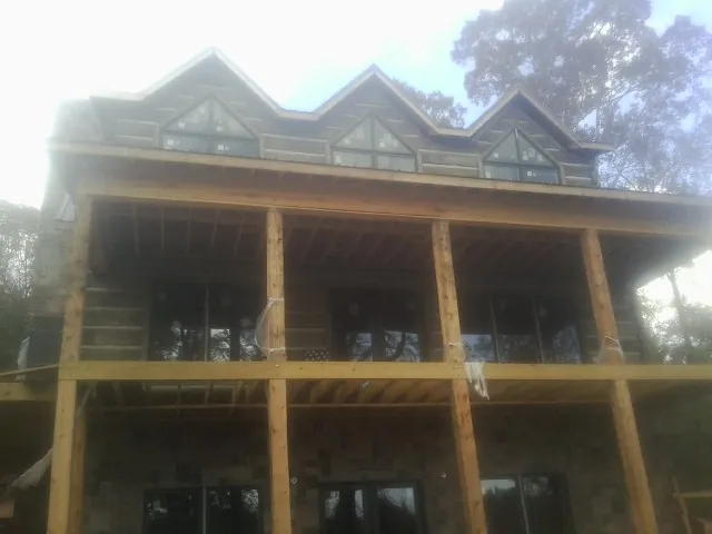 Dormers and porch framing on a large log home under construction — Roof Coating work by our crew in Georgiana