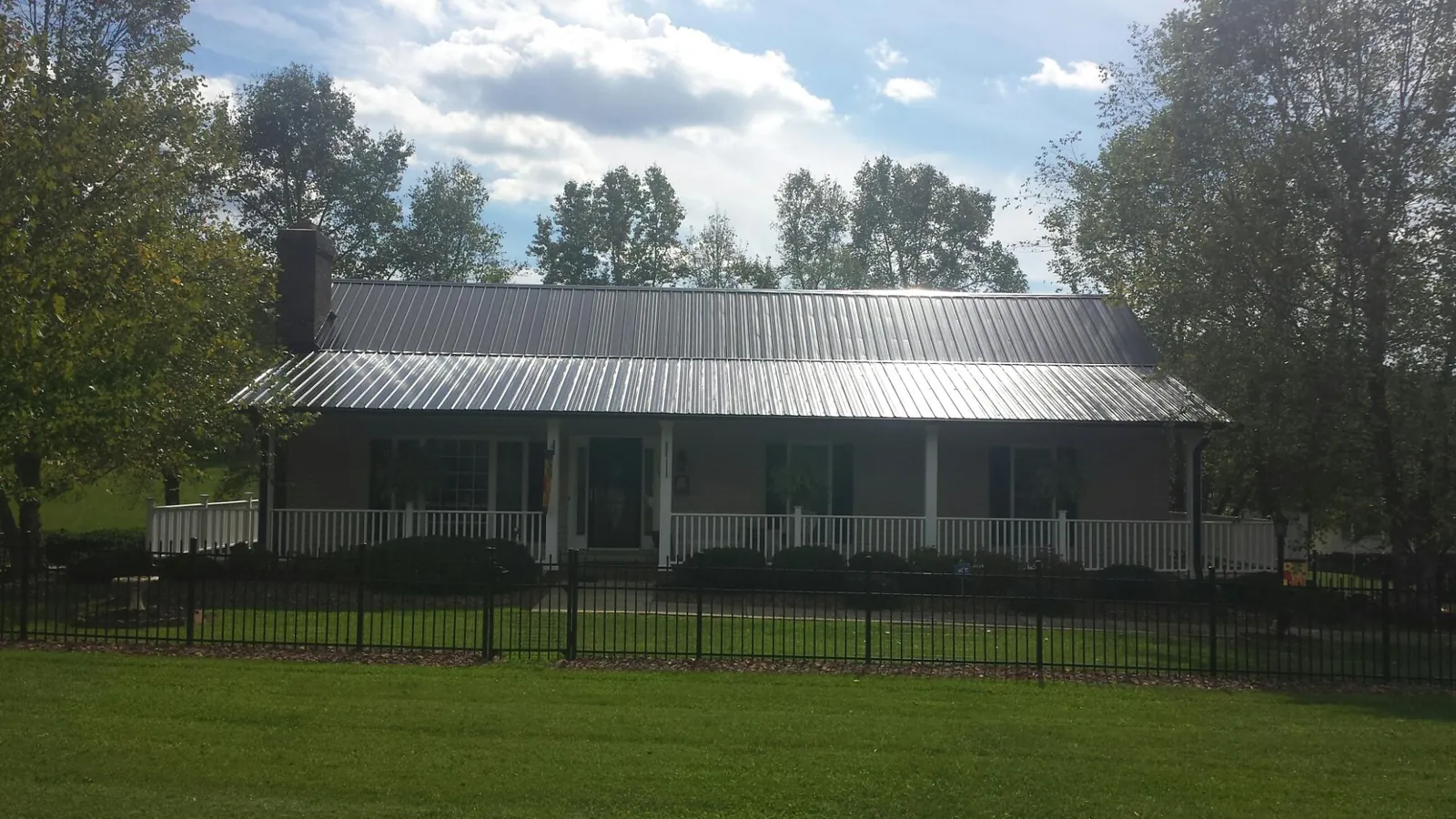 Gray metal roof on a brick ranch with a full width front porch in Georgiana