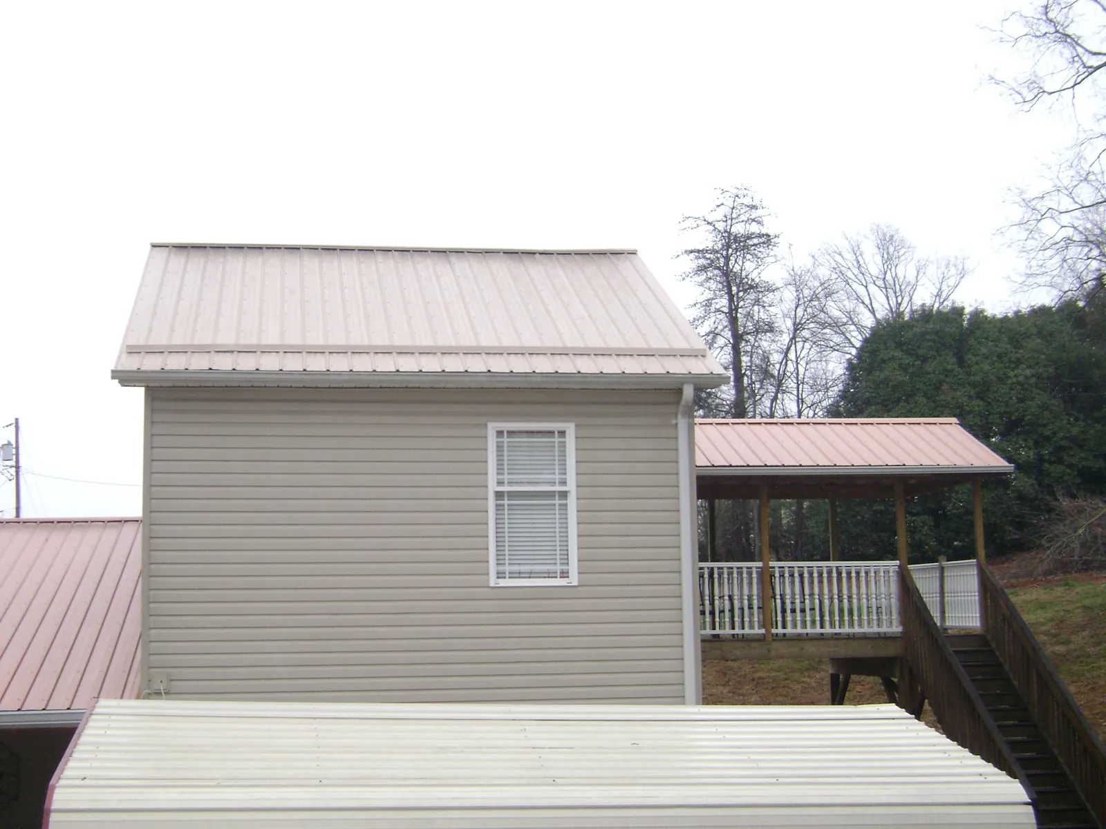 Tan metal roofs on a two story addition and attached porch, from a Roof Replacement job in Georgiana