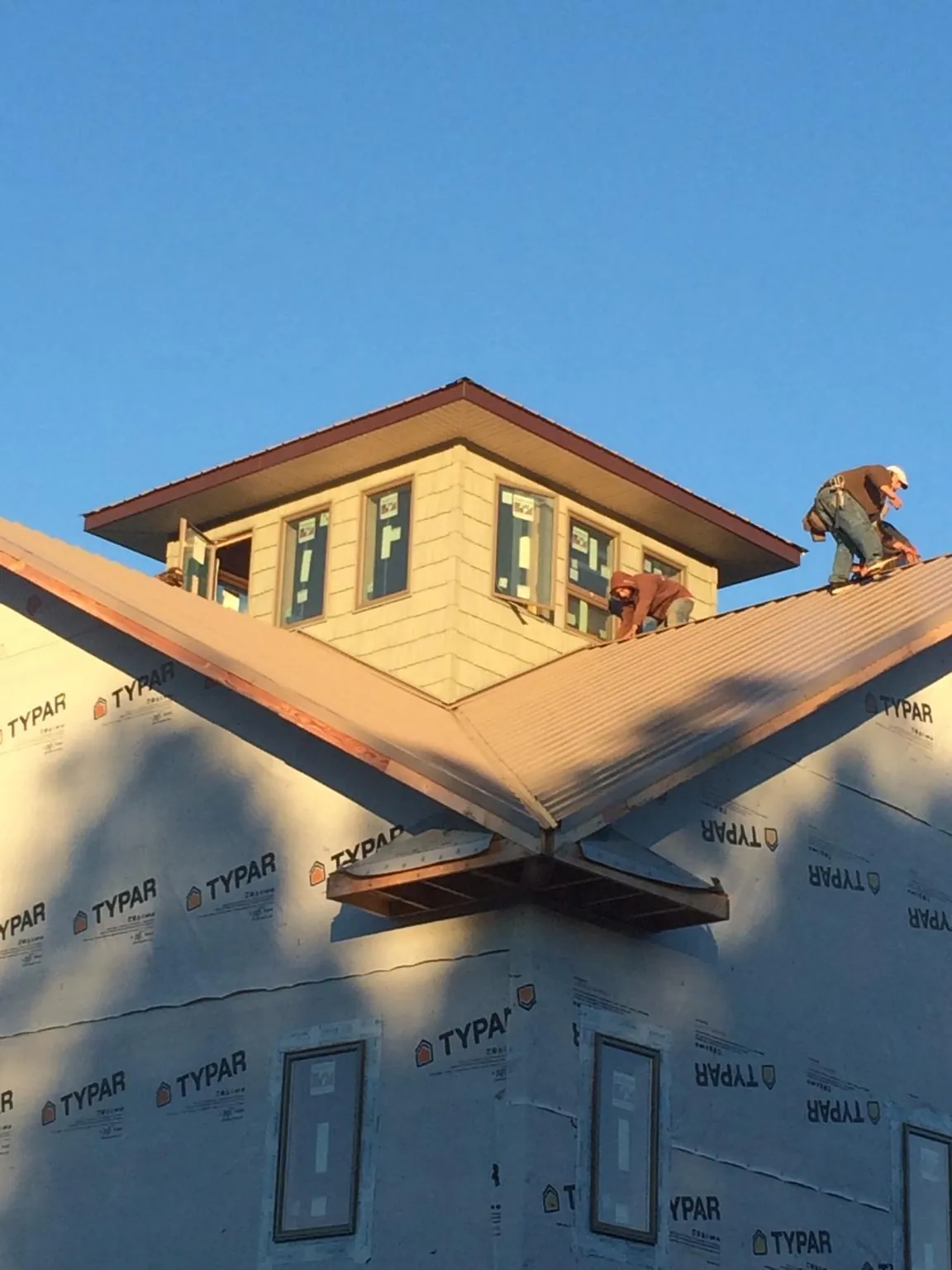 Roofers working around a rooftop cupola on a new metal roof at sunset — Roof Waterproofing in Georgiana by Roofing Brothers